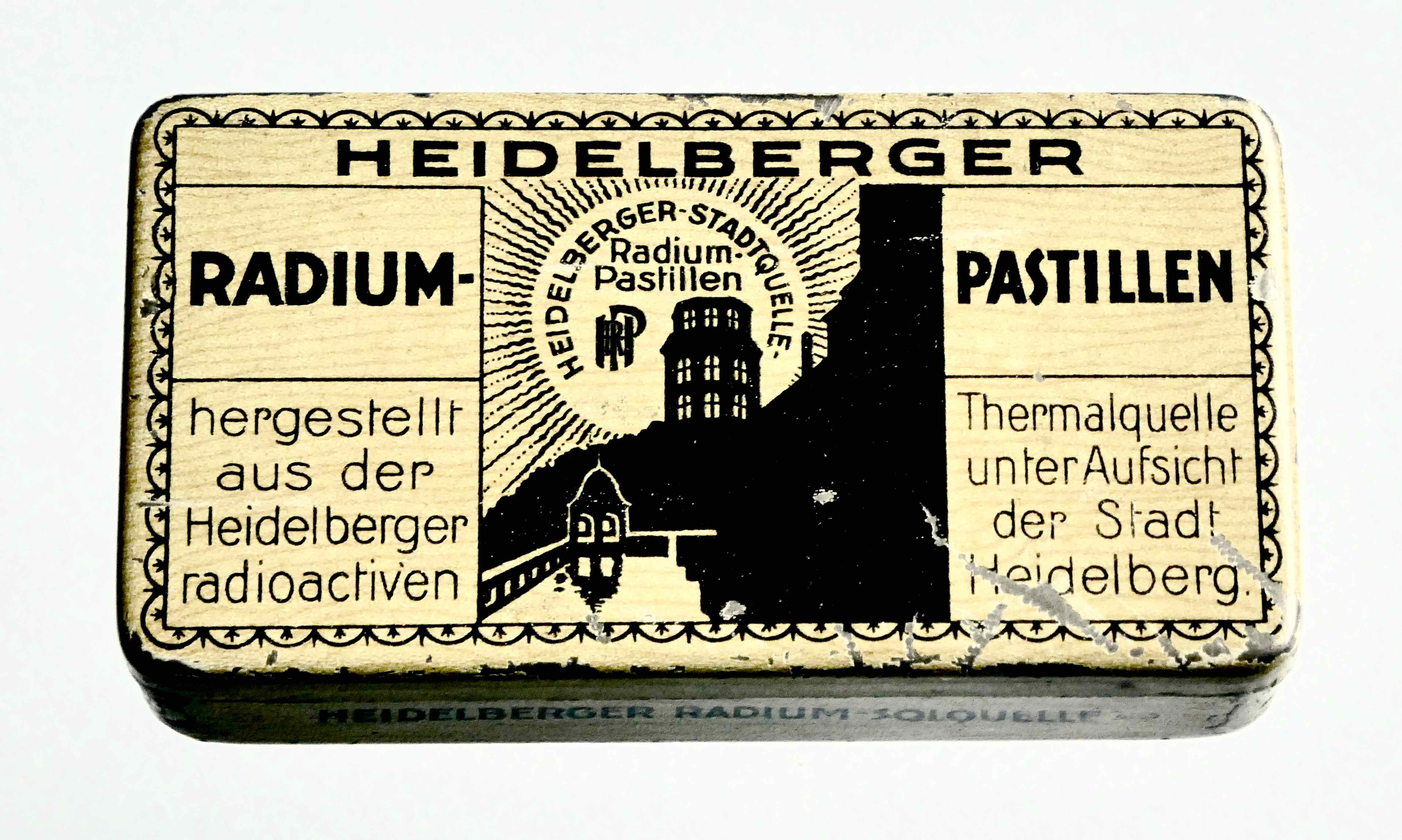 "Heidelberger Radiumpastillen. Wie aus anderen radioaktiven Quellen werden auch aus der Heidelberger Thermalquelle unter städtischer Aufsicht Pastillen hergestellt, die bei Heiserkeit, Gelenkrheumatismus und Gicht sich bewähren sollen." Leere Blechdose (Lutschpastillen), um 1922.