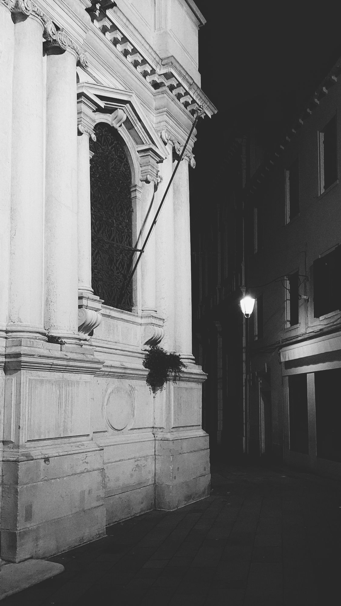 A churches facade, monochrome in a night scenery. A dark alley behind.