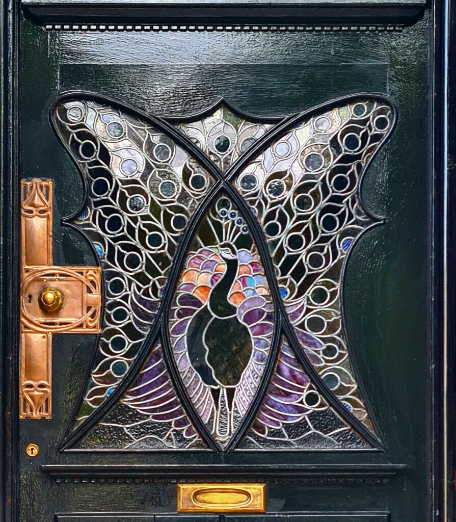 A stained glass Art Nouveau window featuring a peacock.