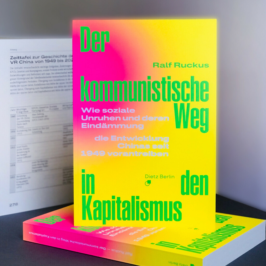 Bücherstapel aus »Der kommunistische Weg in den Kapitalismus. Wie soziale Unruhen und deren Eindämmung die Entwicklung Chinas seit 1949 vorantreiben« von Ralf Ruckus. Im Hintergrund aufgeschlagen: Beginn der mehrseitigen ›Zeittafel zur Geschichte der VR China von 1949 bis 2023‹ im Buch