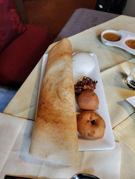 Ein Teller mit südindischen Spezialitäten: Von links nach rechts - Masala Dosa, Idly, Pakoda, Bonda und ein Vada. Im Hintergrund die Soßen dazu