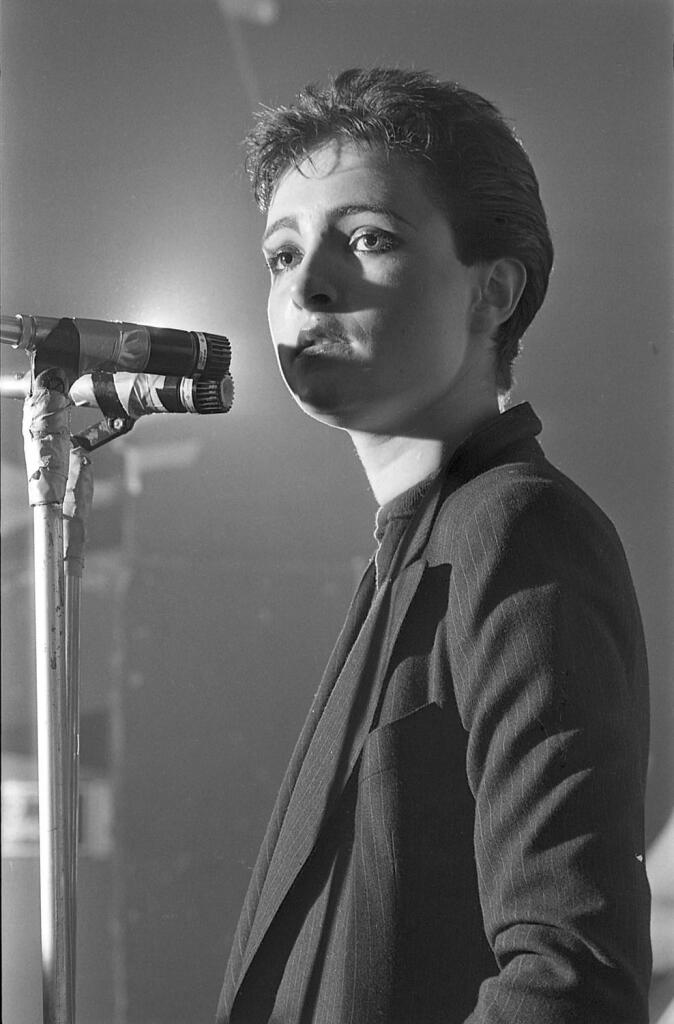 A young woman on stage in front of a microphone stand.