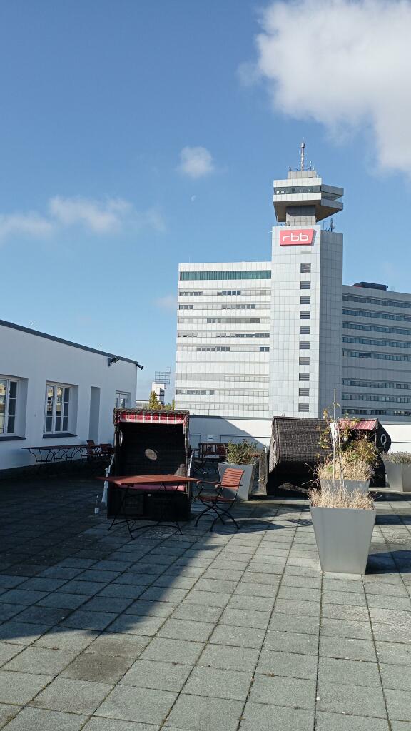 Strandkorb auf Dachterrasse, Westliche Blickrichtung 
Hochhaus mit Aluminium-Fassade, 
mit dem Logo eines ÖR-Medienhauses