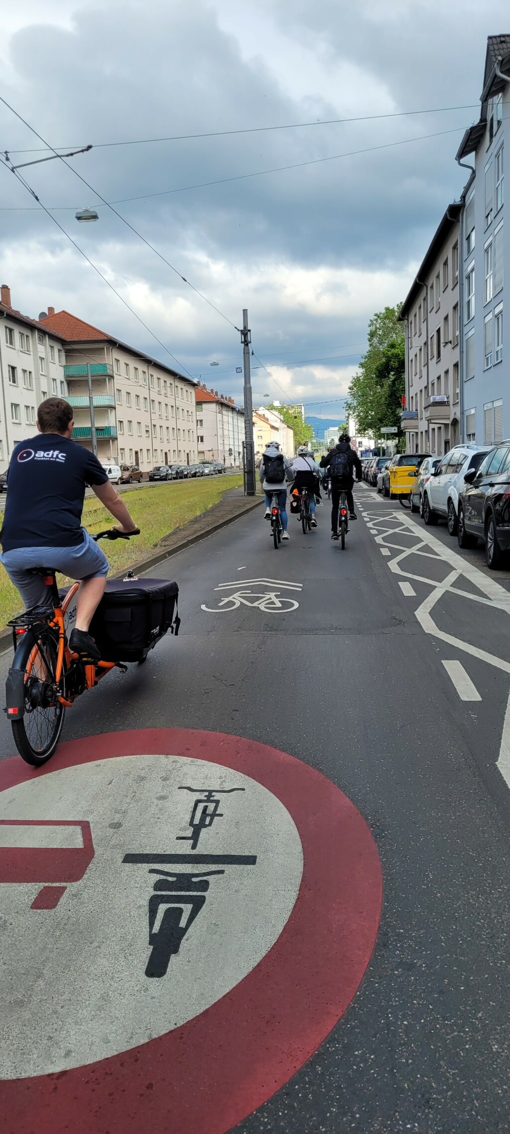 Radfahrende auf der Schloßstraße, auf der Fahrbahn ist das Verkehrszeichen für Überholverbot und ein Sharrow markiert. Die Türzone ist durchgehend mit vielen "X" markiert.