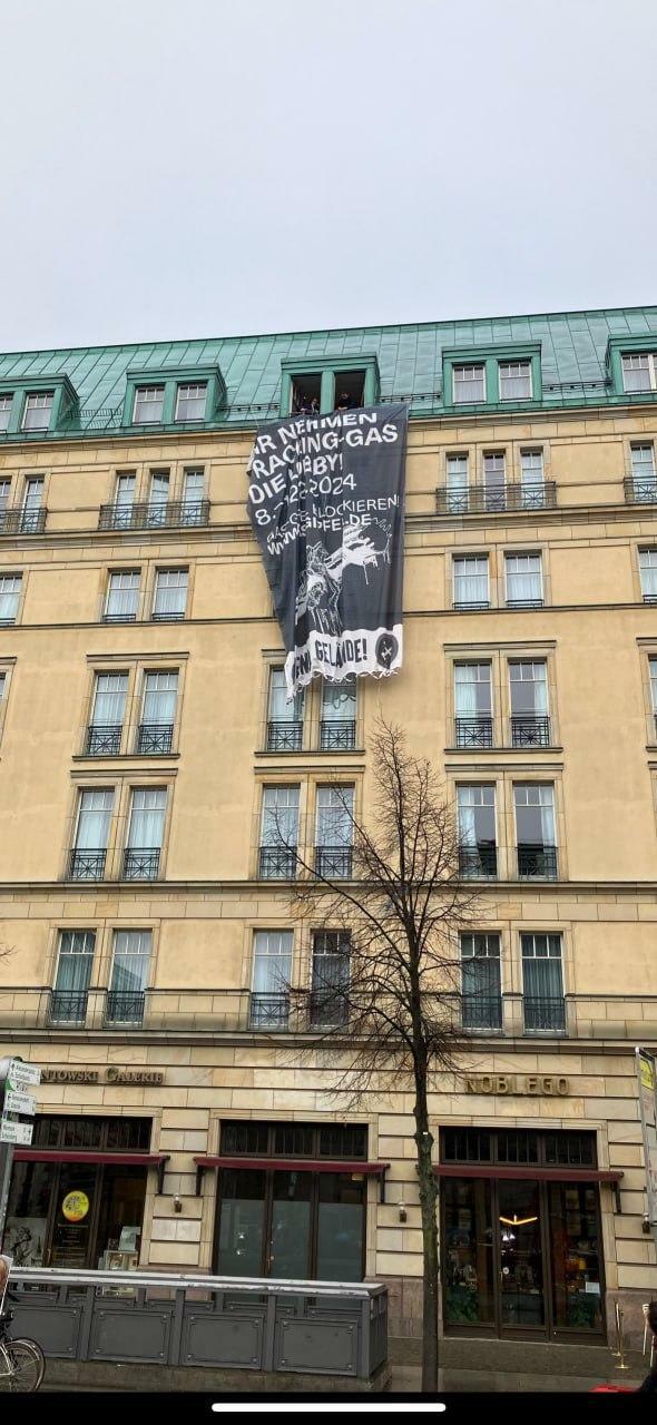 Am Hotel Adlon in Berlin hängt an der Außenfassade ein Banner mit dem Text "Wir nehmen Fracking-Gas die Lobby, 8.-12.12.2024"