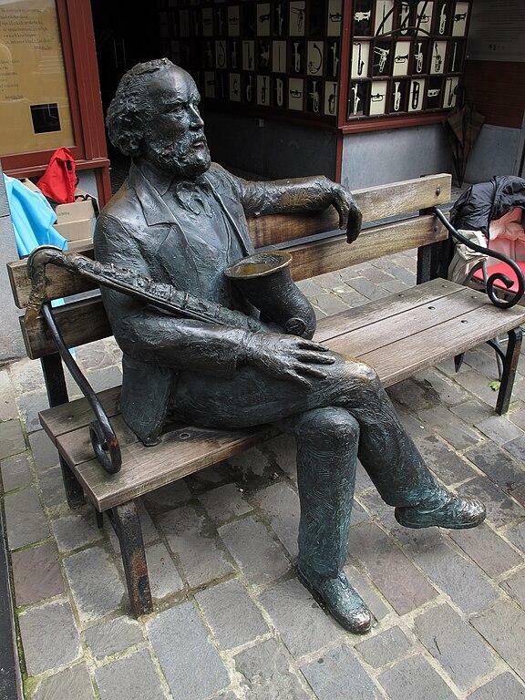 Bronzeskulptur in seinem Geburtsort Dinant: Adolphe Sax mit Saxophon auf einer Bank sitzend 