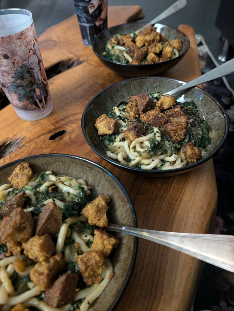 Drei Schalen Udon mit Spinat in Erdnusssauce und Tofuchunks plus gerösteter Sesam on top