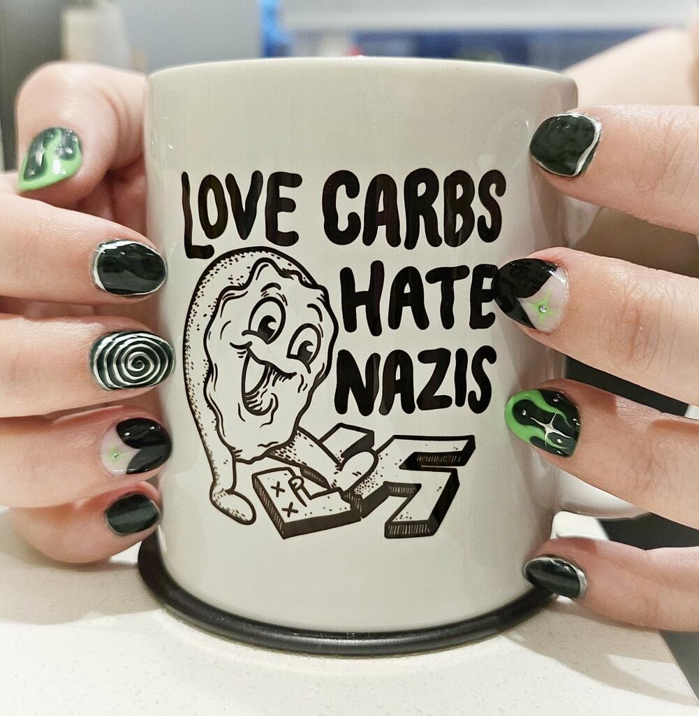 Jen's hands around a coffee mug that says LOVE CARBS, HATE NAZIS