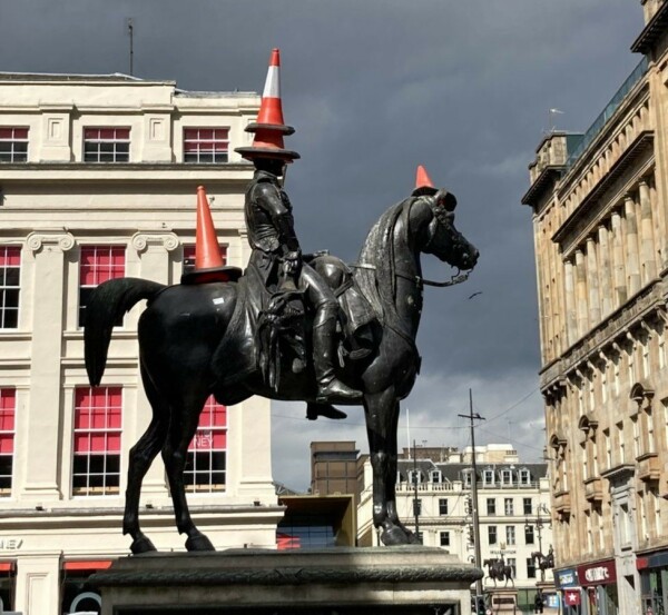 Statue of the Duke of Wellington on a horse in Glasgow with 2 traffic cones on his head. There are also traffic cones on the horse's head and rump.