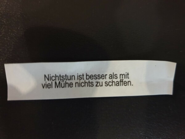 Zettel aus einem Glückskeks mit dem Text: "Nichtstun ist besser als mit viel Mühe nichts zu schaffen."