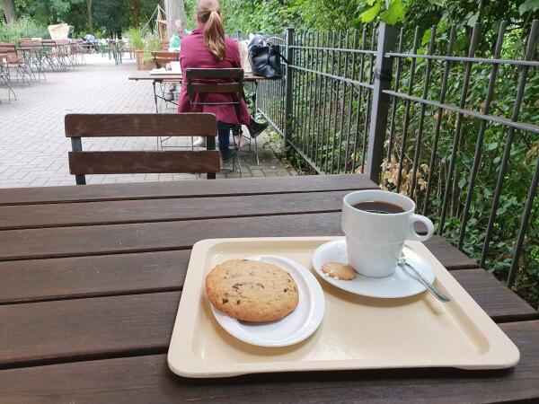 Keks und Becher Kaffee draußen im Cafégarten 