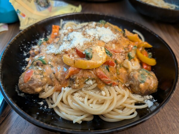 Eine Portion Spaghetti mit Sauce & Käse in einem dunklen tiefen Teller