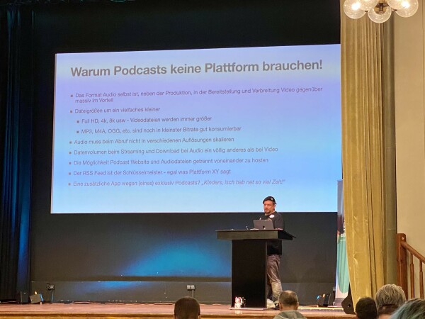 MacSnyder auf der großen Bühne der SUBSCRIBE, mit folgenden Argumenten auf dem Slide:

Warum Podcasts keine Plattform brauchen!
• Das Format Audio selbst ist, neben der Produktion, in der Bereitstellung und Verbreitung Video gegenüber massiv im Vorteil
• Dateigrößen um ein vielfaches kleiner
• Full HD, 4k, 8k usw - Videodateien werden immer größer
- MP3, M4A, OGG, etc. sind noch in kleinster Bitrate gut konsumierbar
• Audio muss beim Abruf nicht in verschiedenen Auflösungen skalieren
• Datenvolumen beim Streaming und Download bei Audio ein völlig anderes als bei Video
• Die Möglichkeit Podcast Website und Audiodatelen getrennt voneinander zu hosten
• Der RSS Feed ist der Schlüsselmeister - egal was Plattform XY sagt
• Eine zusätzliche App wegen (eines) exklusiv Podcasts? „Kinders, isch hab net so viel Zeit!"