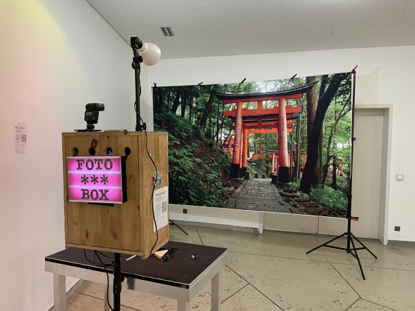 A wooden box stands on a table opposite a photo background showing a Japanese shrine in a forest. The 'wooden box' is actually my photo box