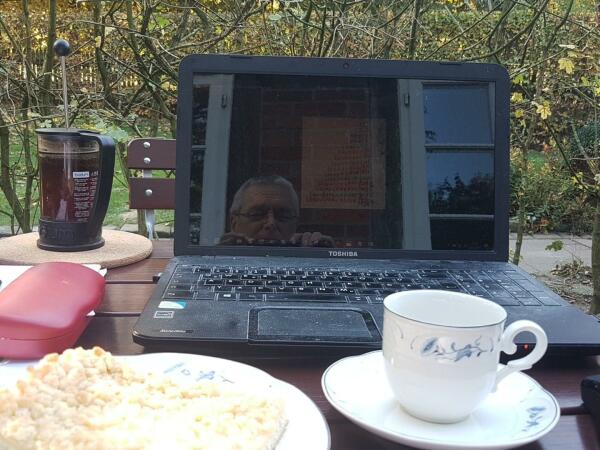 Preßkanne, Brillenetui, Laptop, Stück Kuchen, Tasse Kaffee draußen im Herbst