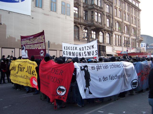 Antifa-Demonstrationszug mit einem Transpi mit der Aufschrift "koksen, kotzen, kommunismus – luxus für alle – kapitalismus abschaffen"