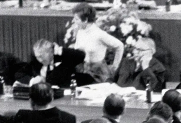 Ein schwarz-weiss Foto von dem Moment, in dem Beate Klarsfeld die Ohrfeige ausführt und Kiesinger erschrocken die Hand an seinen Kopf führt. 